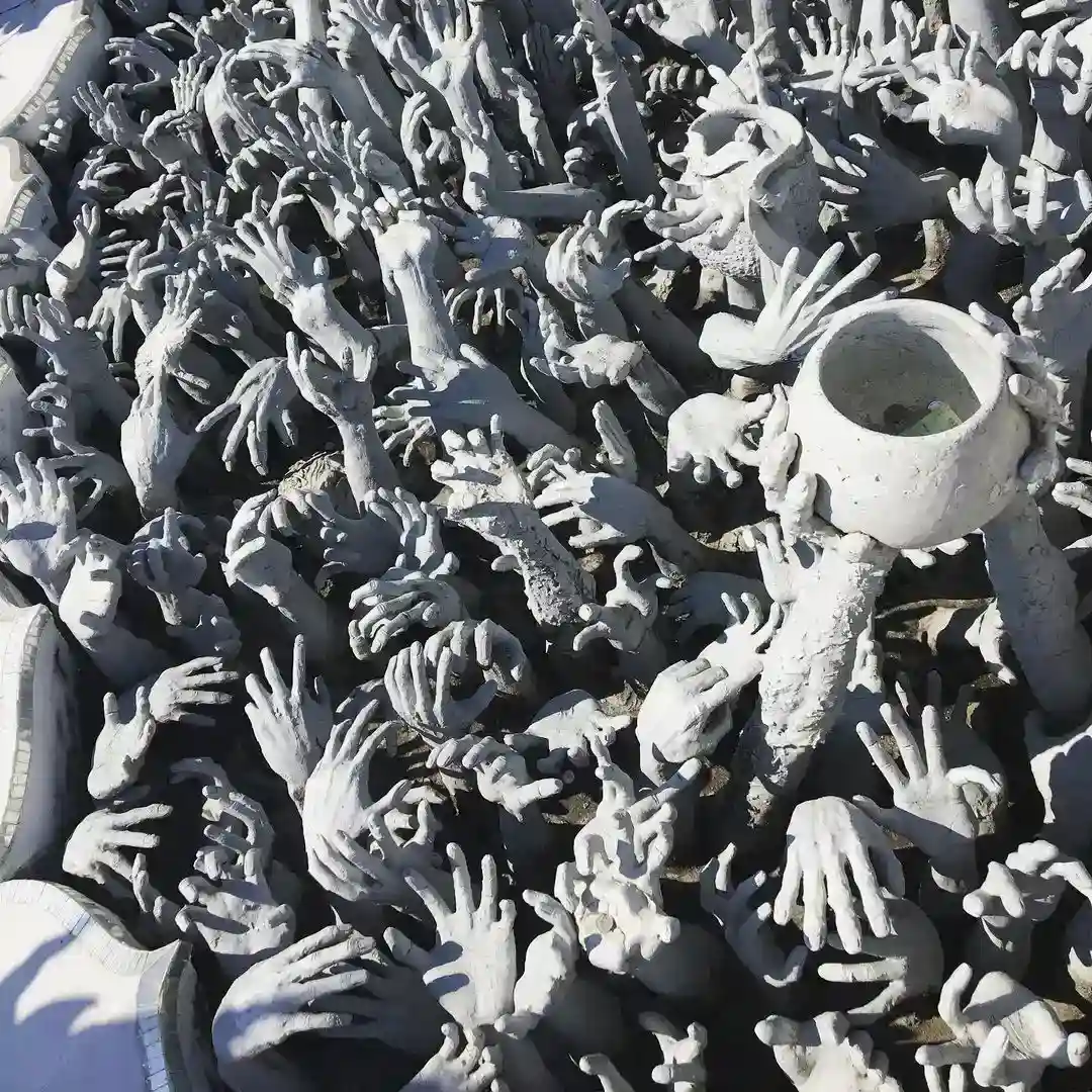 esculturas de manos en el puente del templo blanco